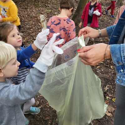 Kita Regenbogen - Mehrere Kindern werfen den gesammelten Müll in einen Beutel. 