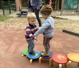 Bild vergr&ouml;&szlig;ern: Zwei Kinder stehen auf Hockern und halten sich an den H&auml;nden.