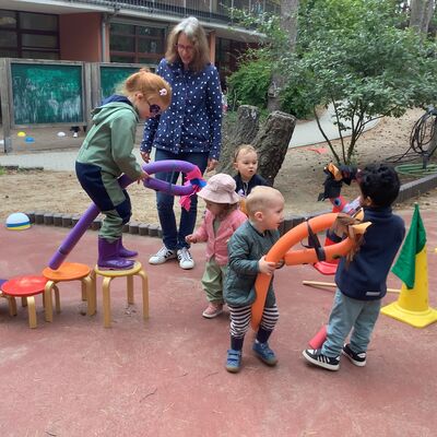 Bild vergr&ouml;&szlig;ern: Mehrere Kinder spielen mit Steckenpferden, eine erwachsene Person schaut dabei zu.