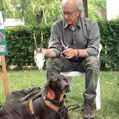 Bild vergr&ouml;&szlig;ern: Der J&auml;ger sitzt neben seinem Hund und zeigt einen Tiersch&auml;del.