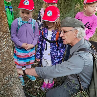 Bild vergr&ouml;&szlig;ern: Der J&auml;ger zeigt den Kindern eine Wildmarkierung am Baum.