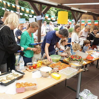 Bild vergr&ouml;&szlig;ern: Eltern und Kinder stehen am leckeren Buffet.