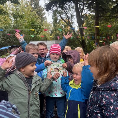 Bild vergr&ouml;&szlig;ern: Die Kinder halten stolz die Plakette hoch und freuen sich.