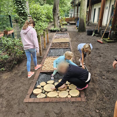 Bild vergr&ouml;&szlig;ern: Kinder bef&uuml;llen den Barfu&szlig;pfad mit verschiedenen Naturmaterialien.