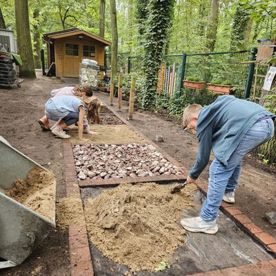 Bild vergr&ouml;&szlig;ern: Kinder bef&uuml;llen den Barfu&szlig;pfad mit Sand.