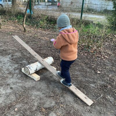 Bild vergr&ouml;&szlig;ern: ein Kind balanciert mit einem Ei auf einem L&ouml;ffel &uuml;ber eine kleine Wippe