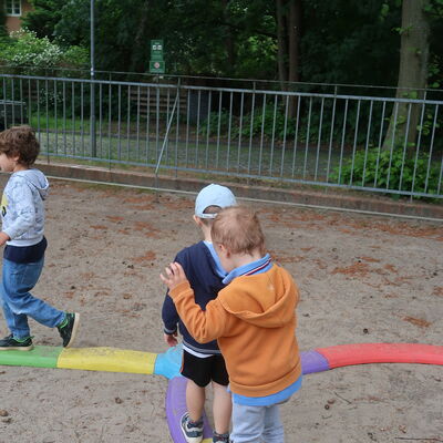 Bild vergr&ouml;&szlig;ern: Kinder balancieren hintereinander auf einem bunten, zusammengesteckten Balancierpfad.