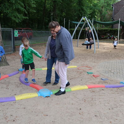 Bild vergr&ouml;&szlig;ern: Kinder der Kita Spielhaus und Bewohner der Lebenshilfe balancieren auf einem bunten Balancierpfad.