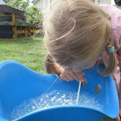 Bild vergrößern: Kita "Kükennest" - Sommerfest - Kind pustet Seifenblasen